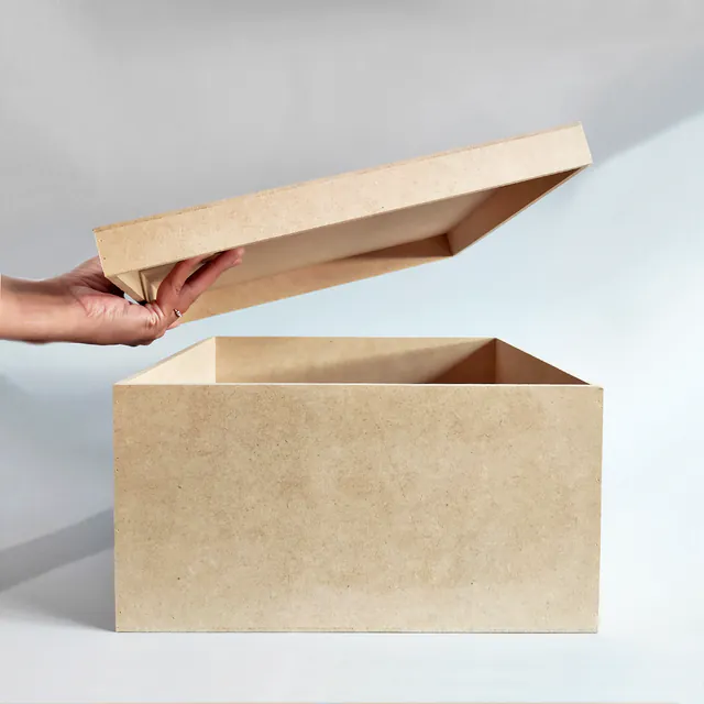 Una mano levanta la tapa de una caja grande de MDF y deja ver el interior vacío