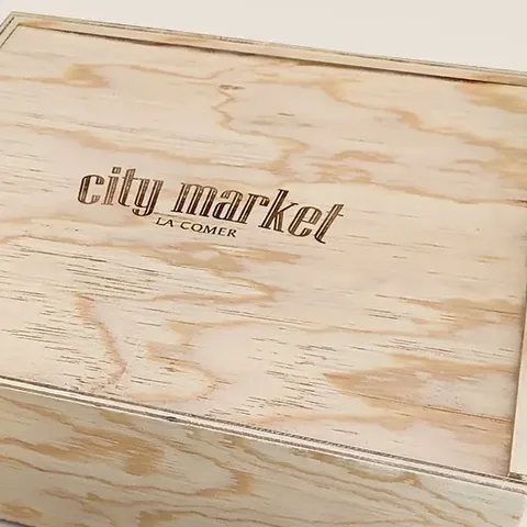 Detalle de la tapa de triplay de pino natural, con su veta y el logotipo grabado, de una caja hecha para City Market