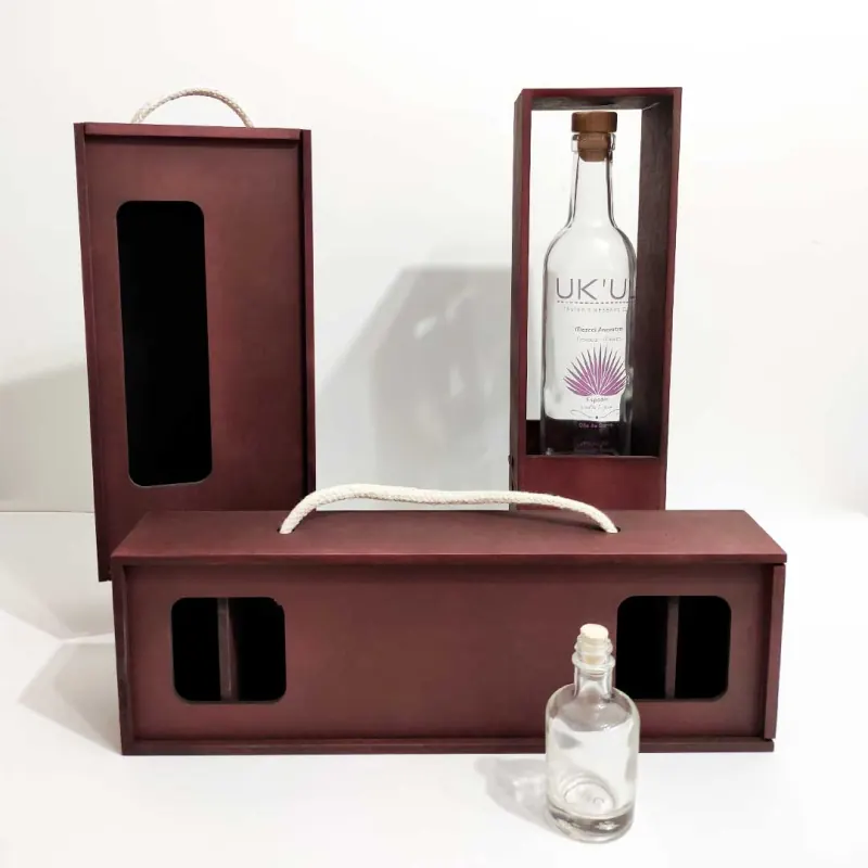 Empaques de UKUL en MDF tintado: una caja vertical con la botella de mezcal a la vista y otra horizontal con asa